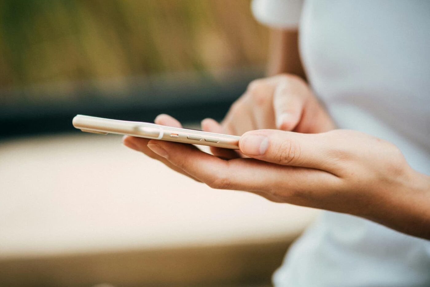 Jemand hält ein Mobiltelefon in der Hand und tippt darauf.